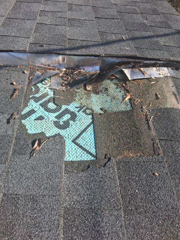 Damaged shingles with synthetic underlayment exposed after wind damage